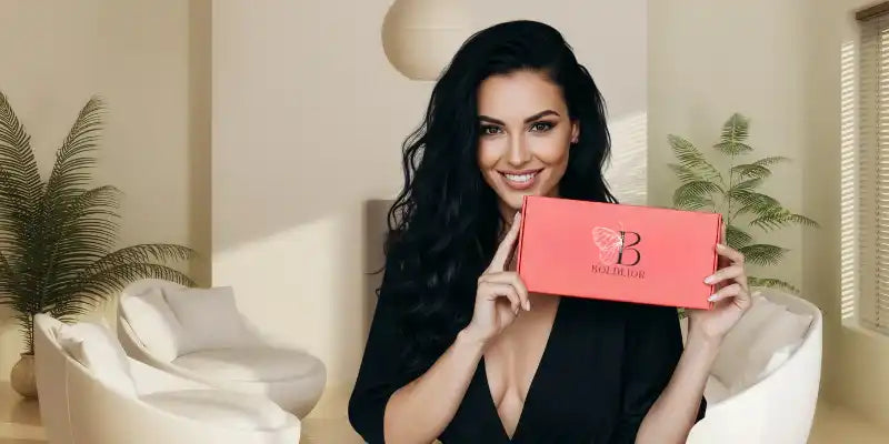 Woman holding a coral-colored gift box.